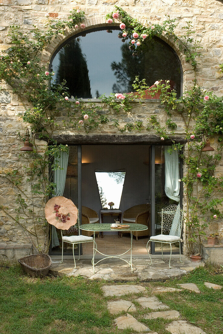 Stone house with rose garland, patio door and metal garden table set