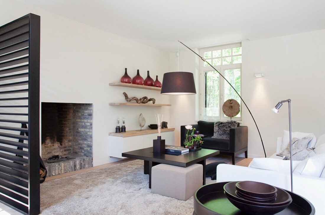Designer living room with arc lamp above dark brown coffee table in front of open fireplace
