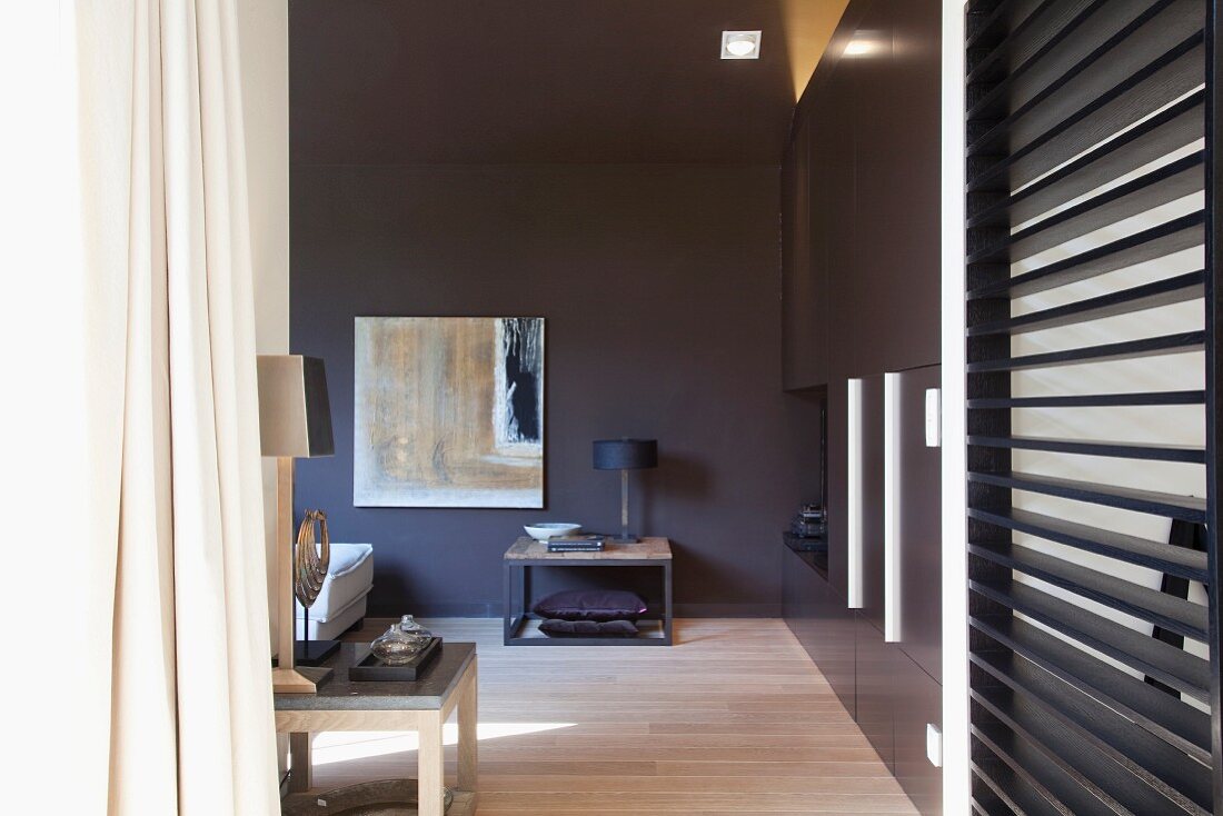 Side table against wall painted dark grey in designer living room with wooden slatted partition