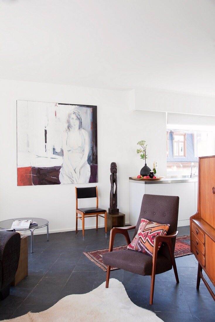 Offener Wohnraum eines Appartements mit moderner Kunst und 50er Jahre Vintagemöbeln auf dunklem Schieferboden