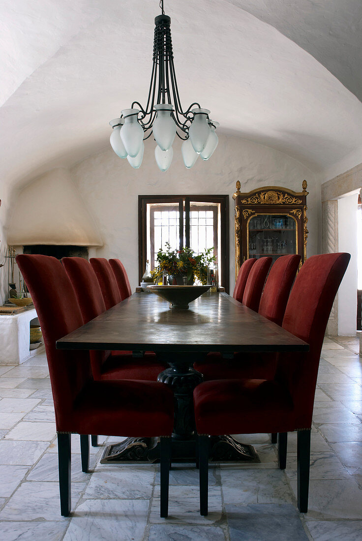 Dining table and chairs with red upholstery in dining room with vaulted ceiling