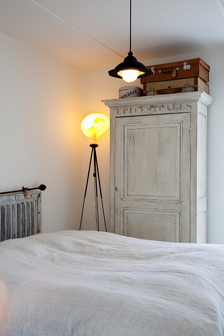 Bedroom with floor lamp and vintage wooden cabinet in white