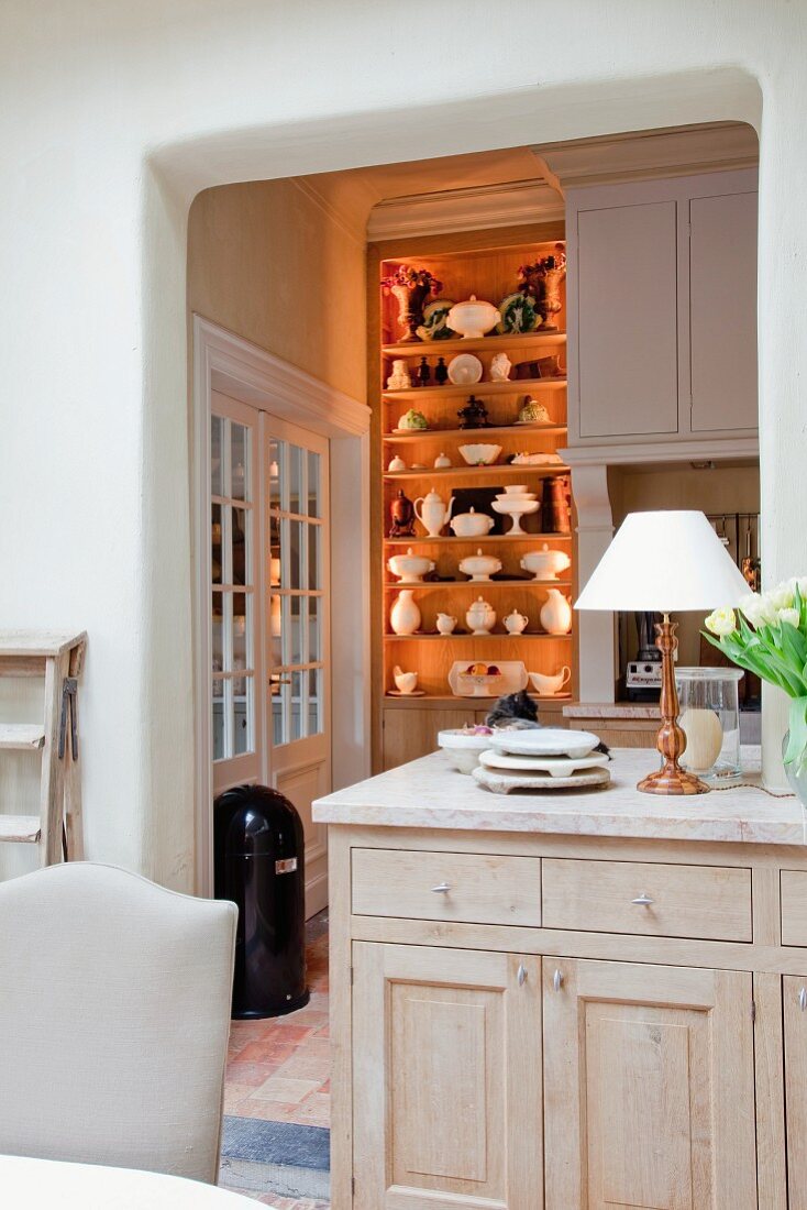 Cabinet in front of open doorway with view of illuminated kitchen shelving