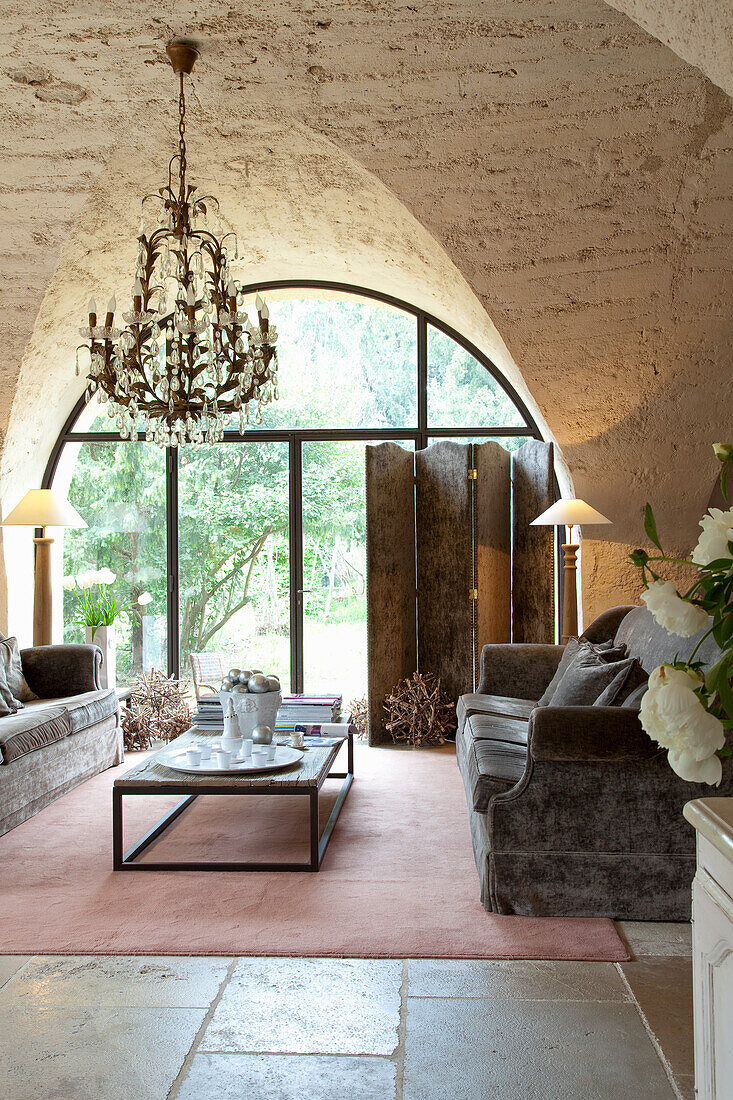 Living room with vaulted ceiling, floor-to-ceiling arched window and rustic furniture