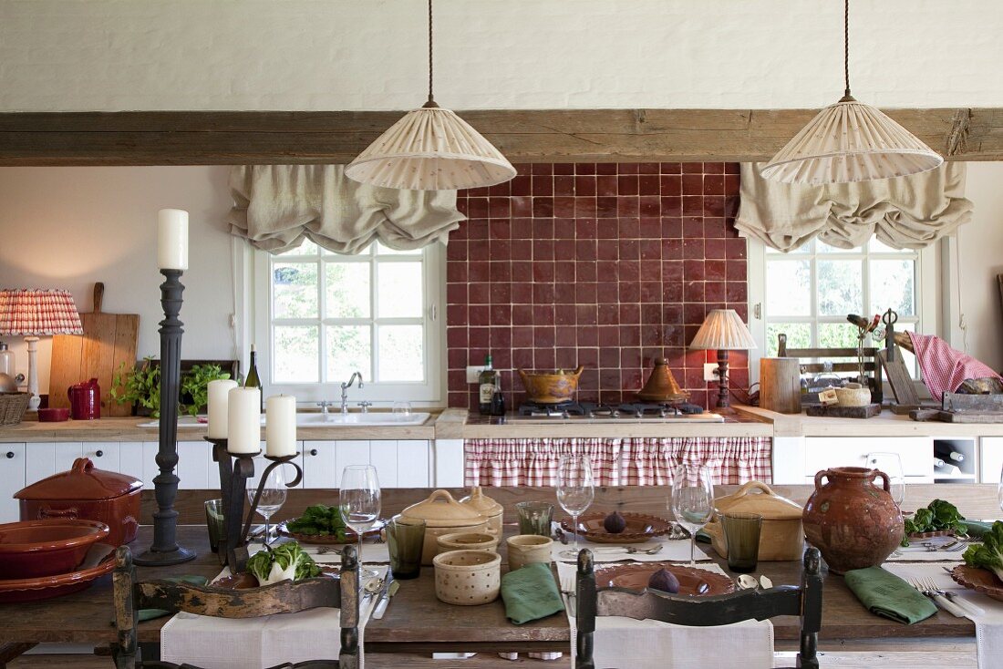 Vintage Hängelampen mit Stoffschirm über gedecktem Tisch mit antiken Holzstühlen in rustikaler Küche