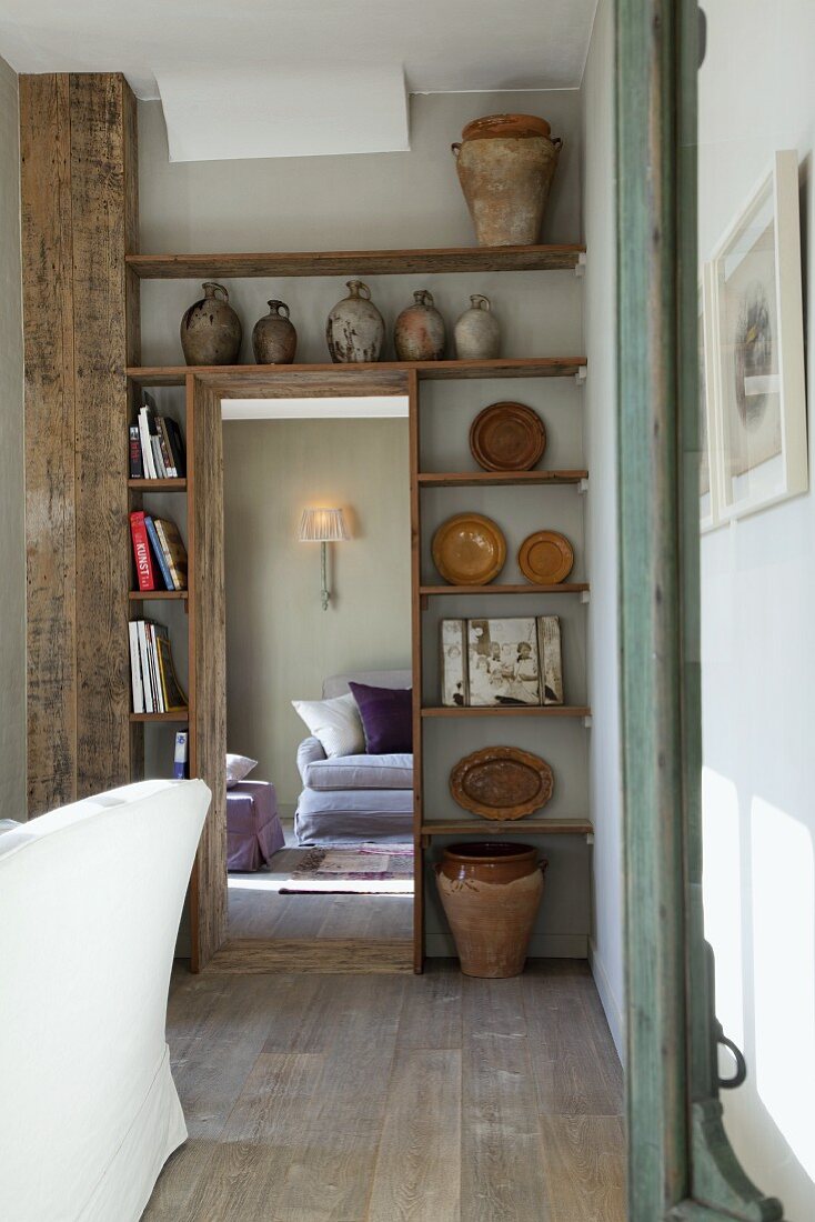 Rustic fitted shelves around open doorway with view into lounge
