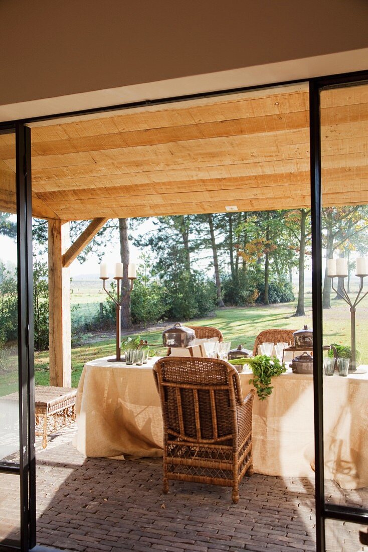 Blick durch offene Terrassentür auf gedeckten Tisch vor ländlichem Garten