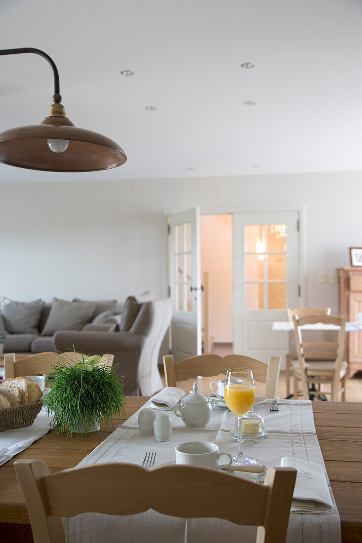 Gedeckter Frühstückstisch mit Orangensaft und frischem Brot