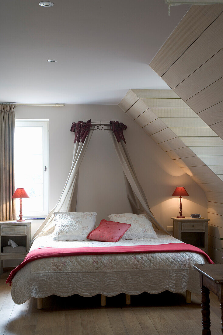 Four-poster bed with red accents in the attic bedroom