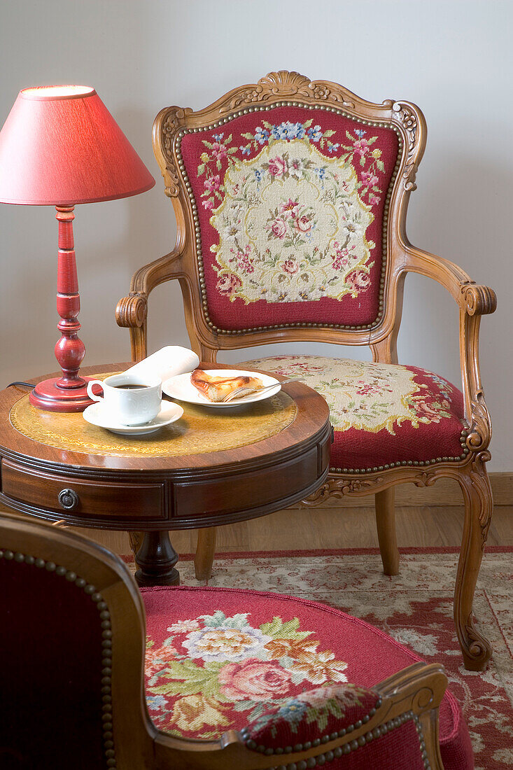 Baroque upholstered armchair with red and gold brocade fabric next to side table