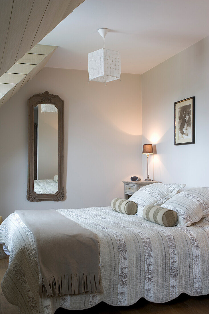 Classically designed bedroom with sloping ceiling and wall mirror