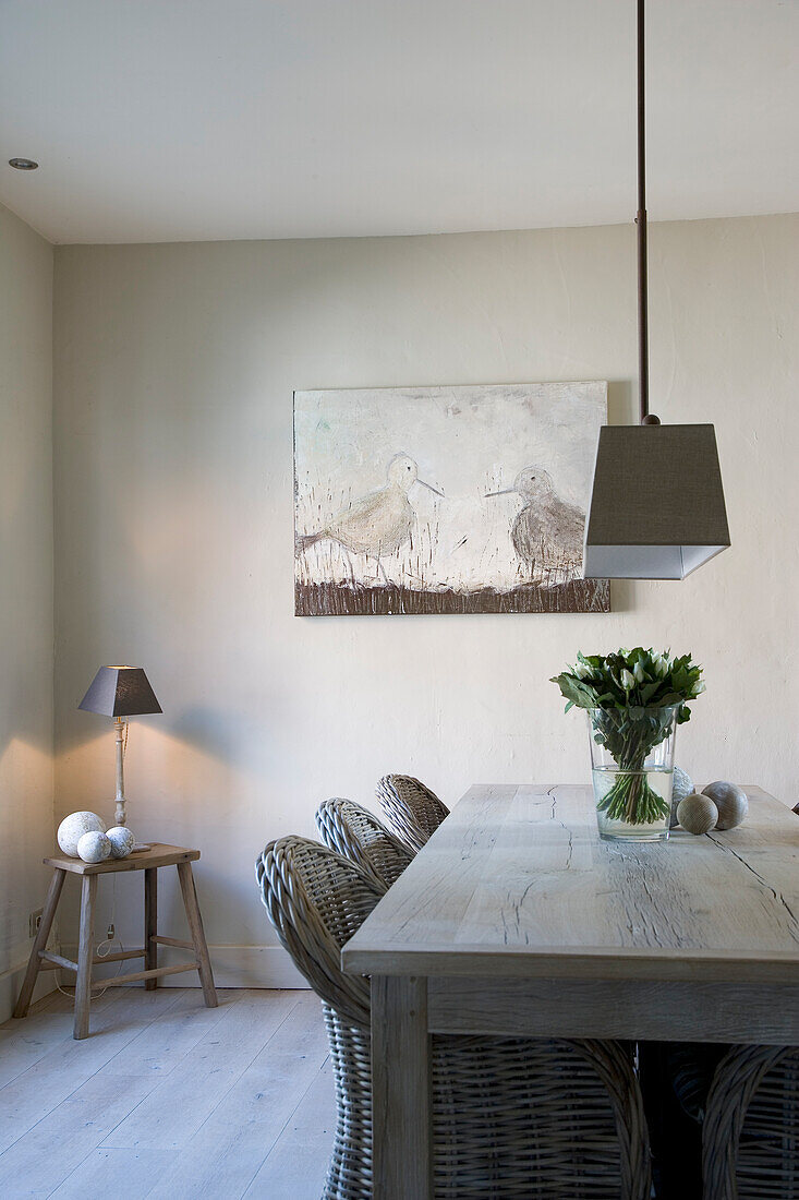 Bleached wood dining table with rattan chairs and animal motif on the wall