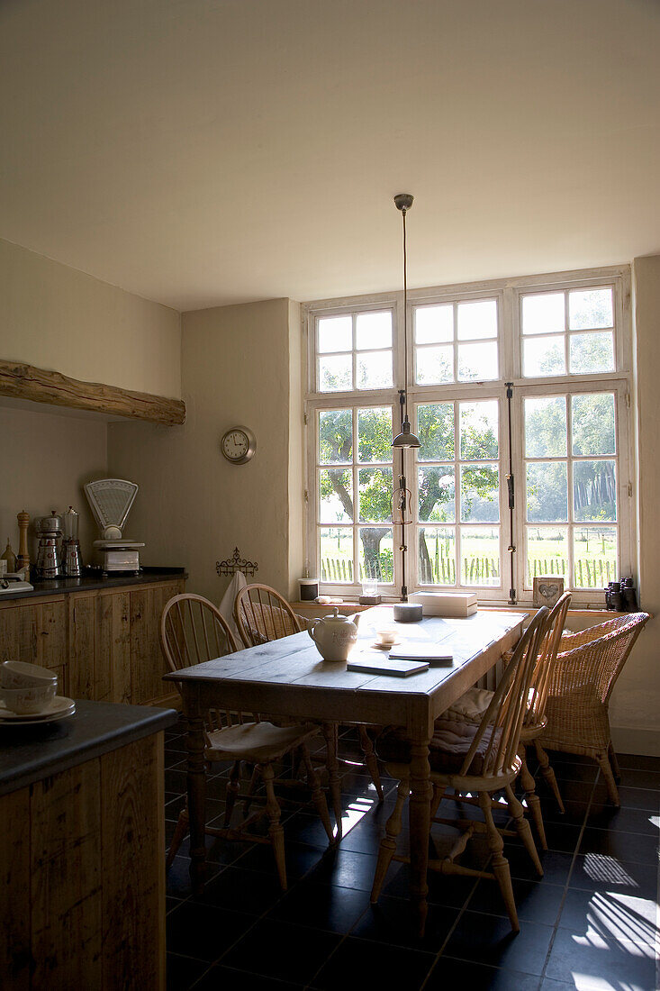 Country kitchen with dining table, wooden and rattan chairs