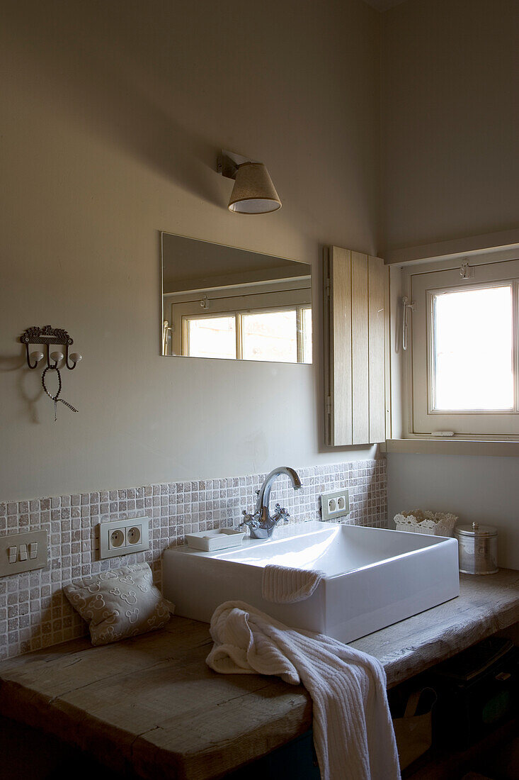 Bathroom with wall tiles and free-standing washbasin on wooden table