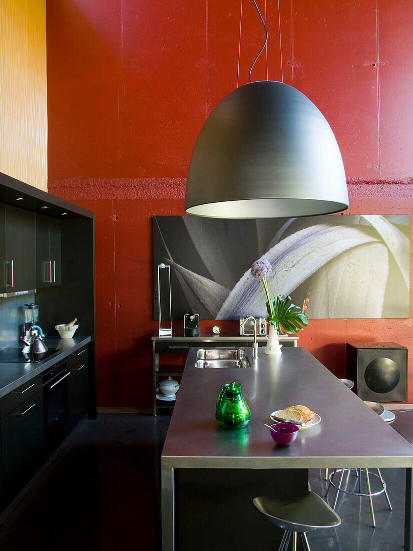 Moderne Küche mit roter Wand und Pendelleuchte