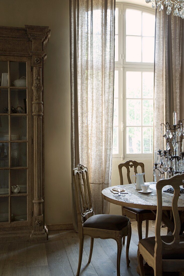 Rococo-style chairs at dining table in front of terrace doors in rustic interior