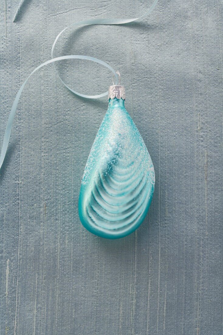 A Christmas tree ornament (a turquoise shell) with a ribbon