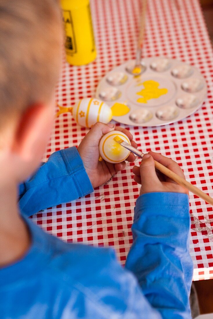 A little boy painting an Easter egg