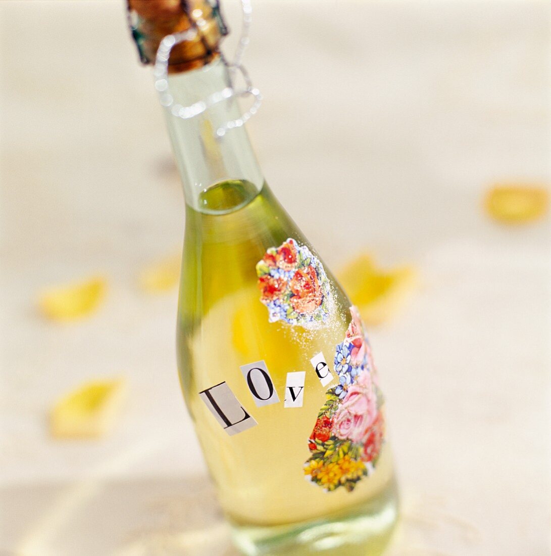 A bottle of sparkling wine decorated with flowers and the word LOVE