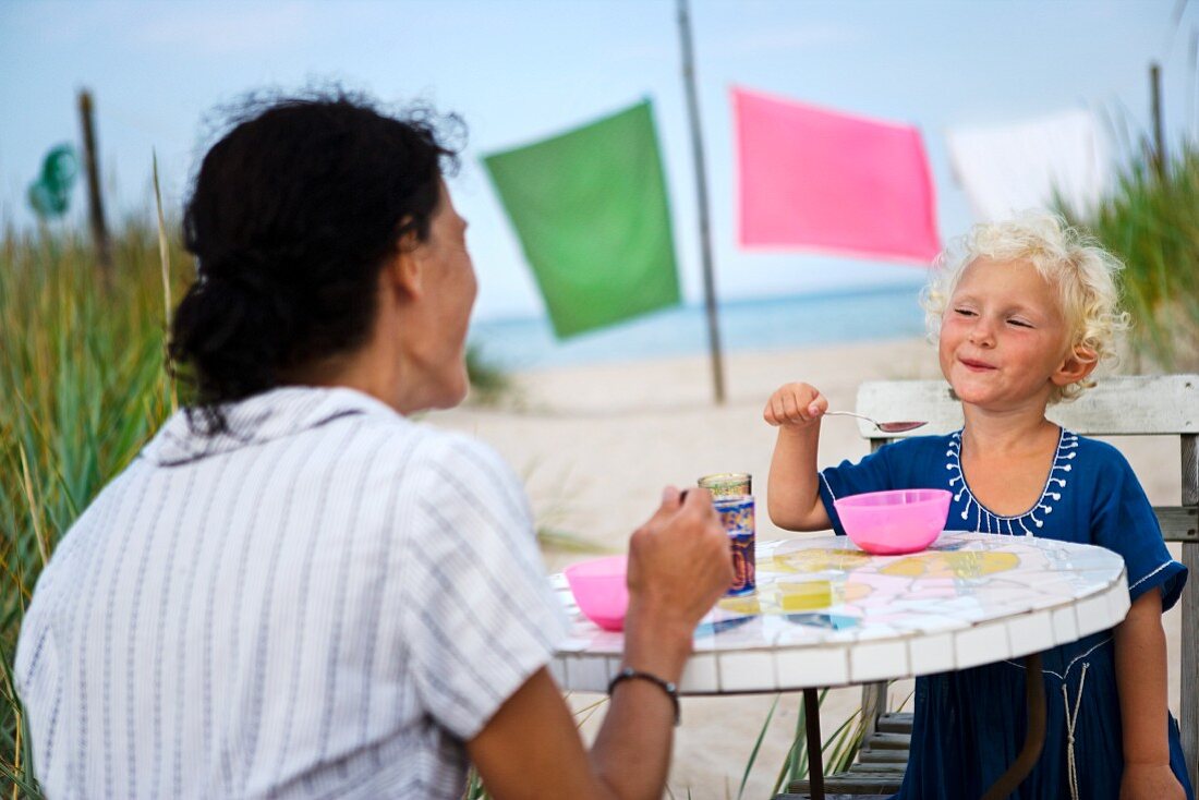 Mutter und Tochter beim Picknick am Strand