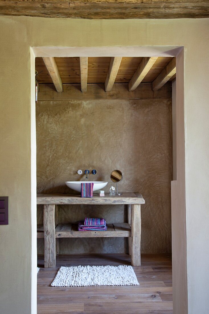 Rustikales Bad ensuite mit moderner Waschschüssel und Wandarmatur auf rustikalem Holztisch
