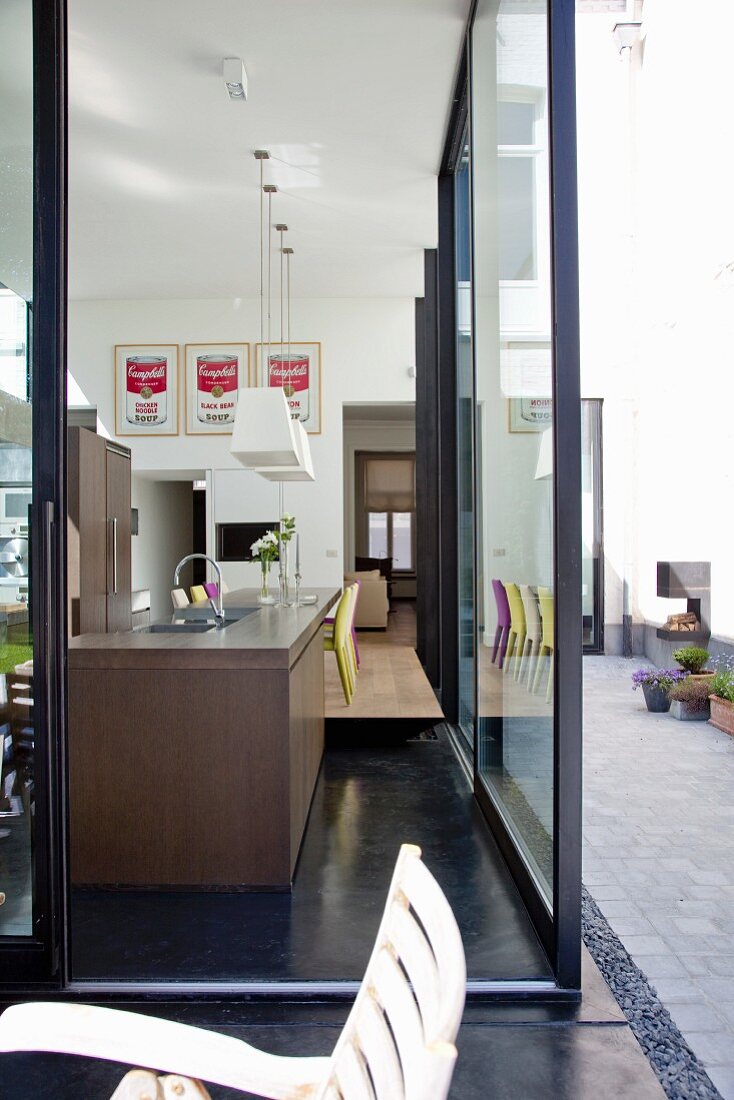 Blick durch Terrassenfenster auf moderne Küchenausstatttung in offenem Wohnraum