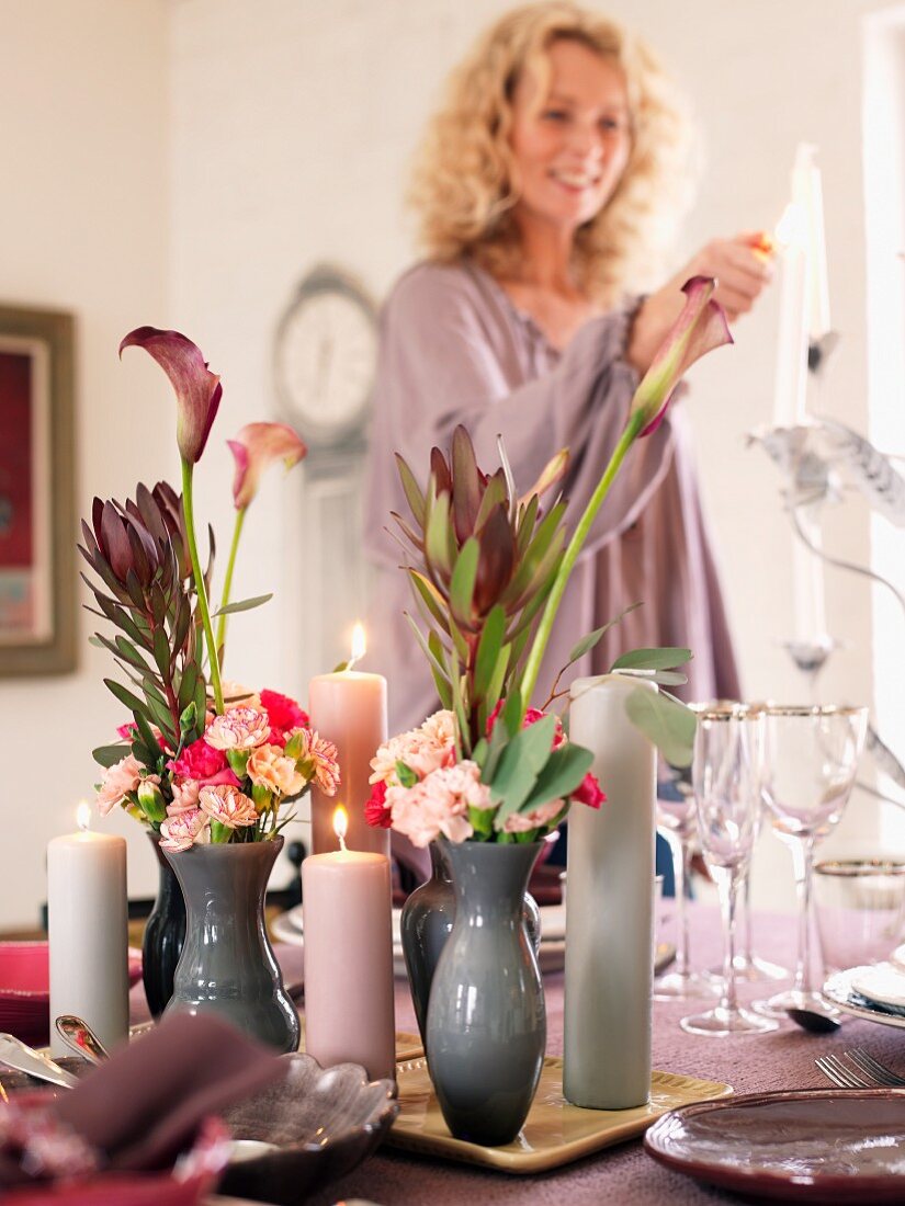 A woman lighting candle on a festively laid table