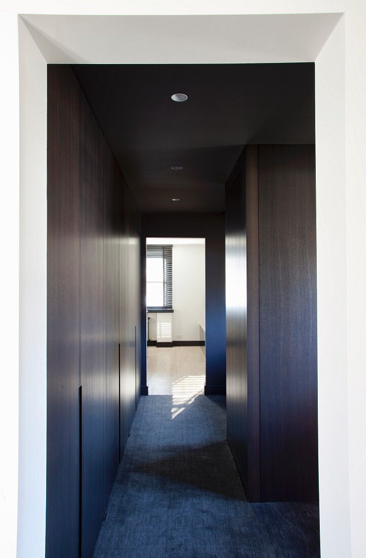 Minimalist hallway with dark wood fitted cupboards