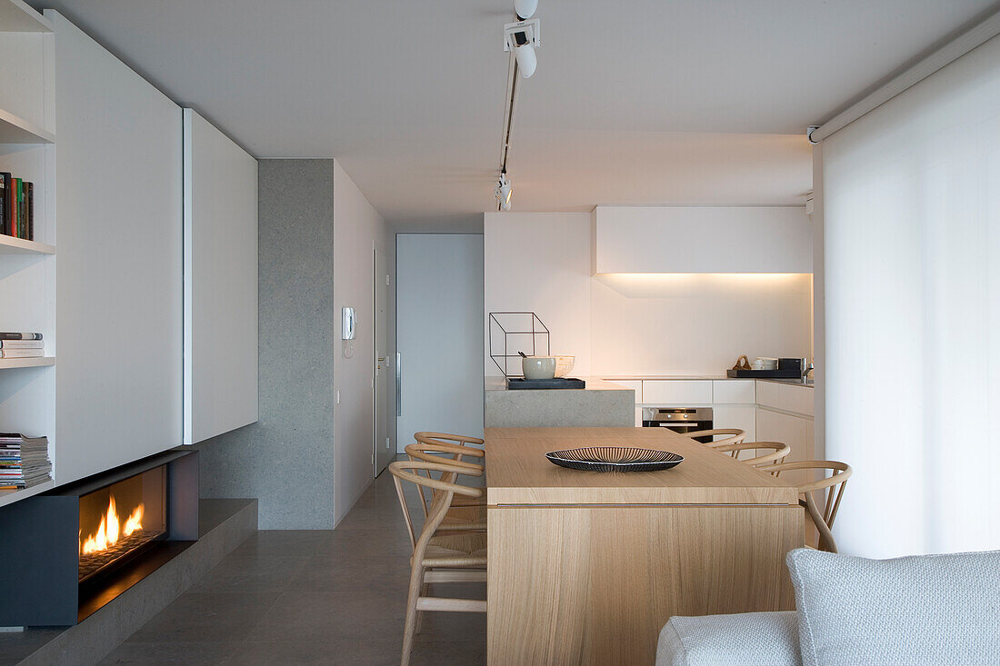 Modern dining area with fireplace and integrated kitchen in neutral colours