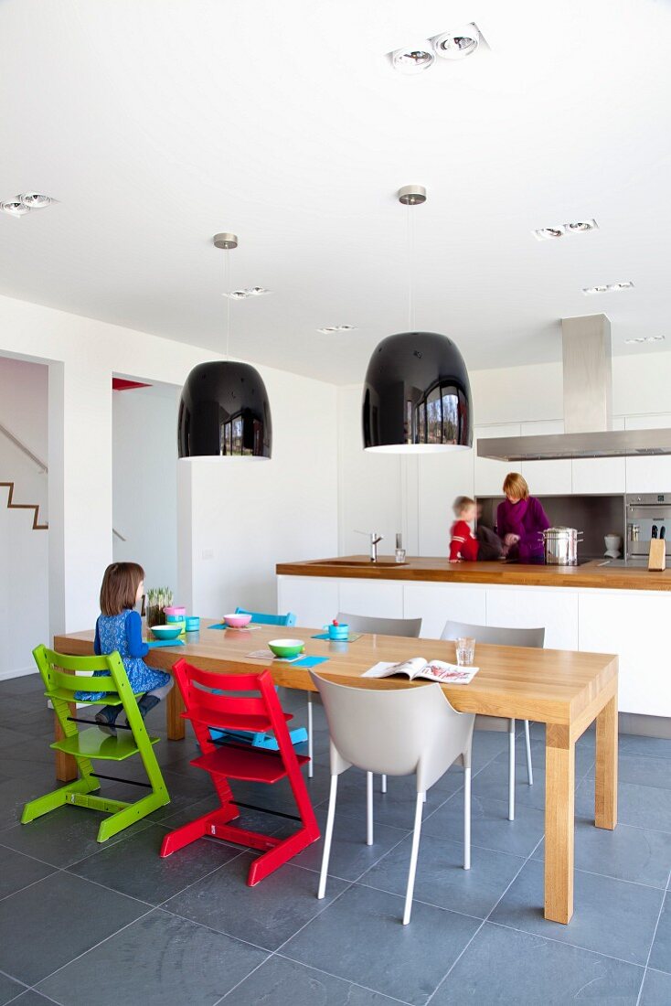 Open-plan kitchen with solid wooden table and brightly coloured children's chairs