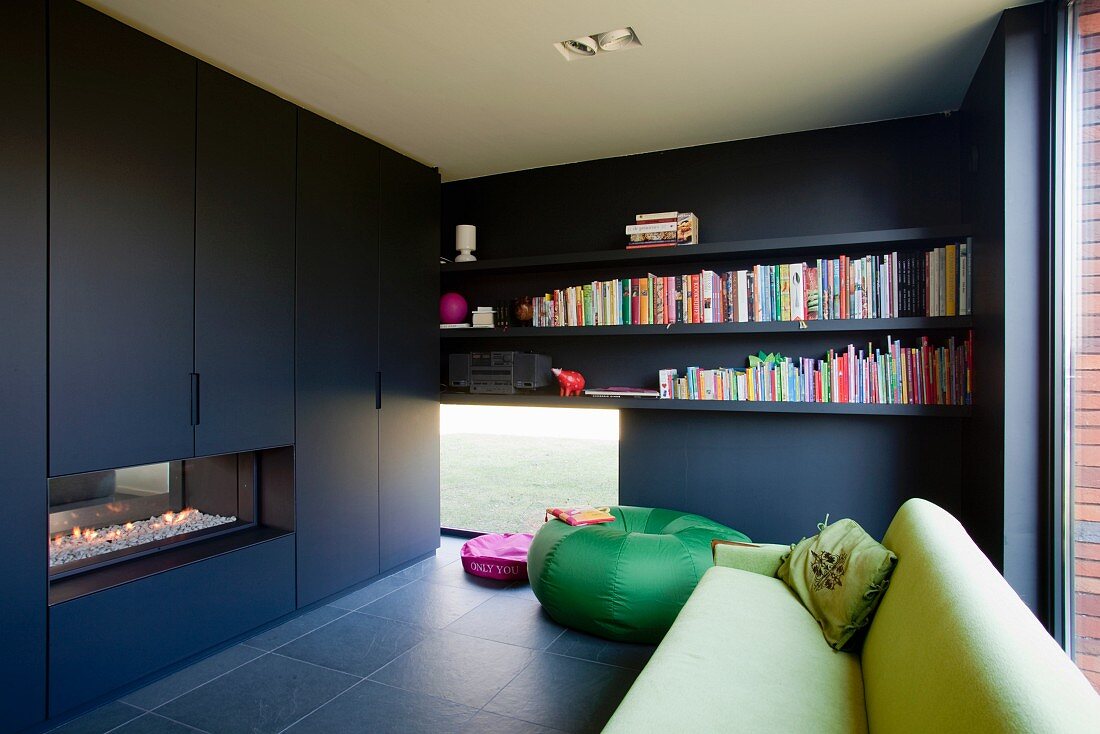 Black fitted cupboards with integrated fireplace opposite green sofa