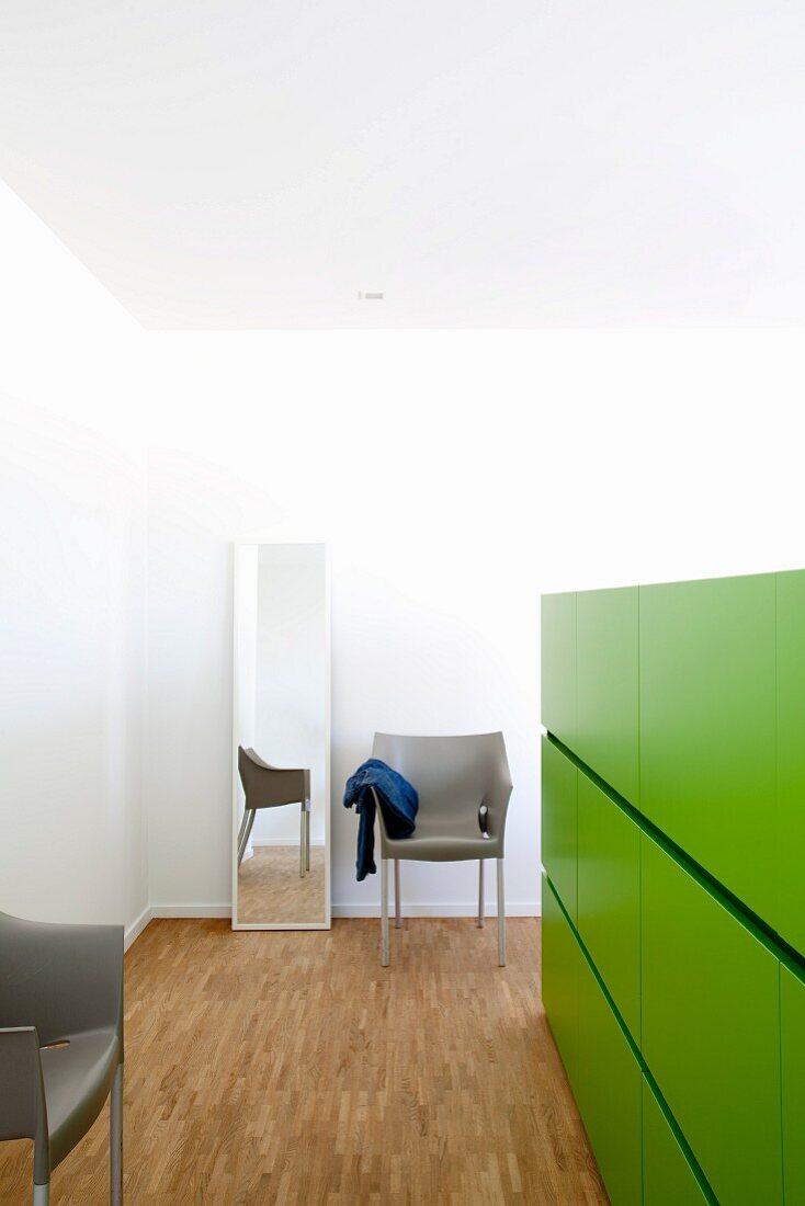 Half-height green partition with integrated drawers in bedroom