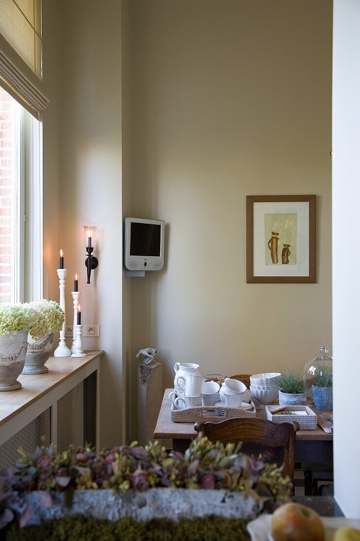 Dining area next to window with country-house ornaments and small monitor in corner of room