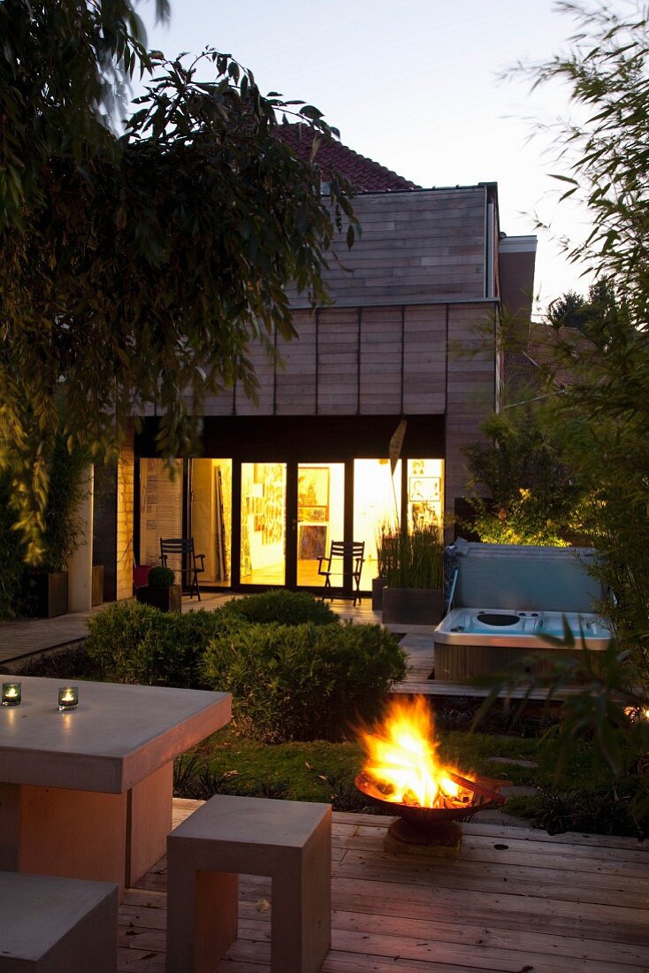 Terrace with outdoor furniture in front of lit fire bowl at twilight