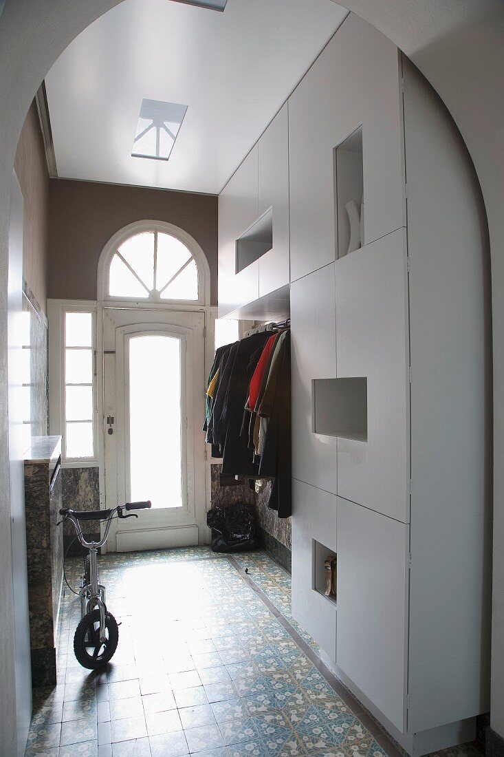 Stilmix im Wohnungsflur mit glattem, weißem Garderobenschrank und verglaster Eingangstür im alten Stil mit Rundbogenfenster