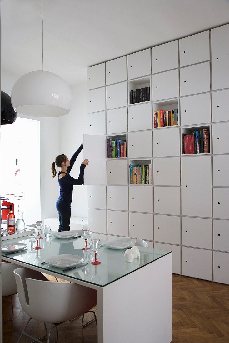 Floor-to-ceiling cupboards with several open shelf compartments in modern, white dining room