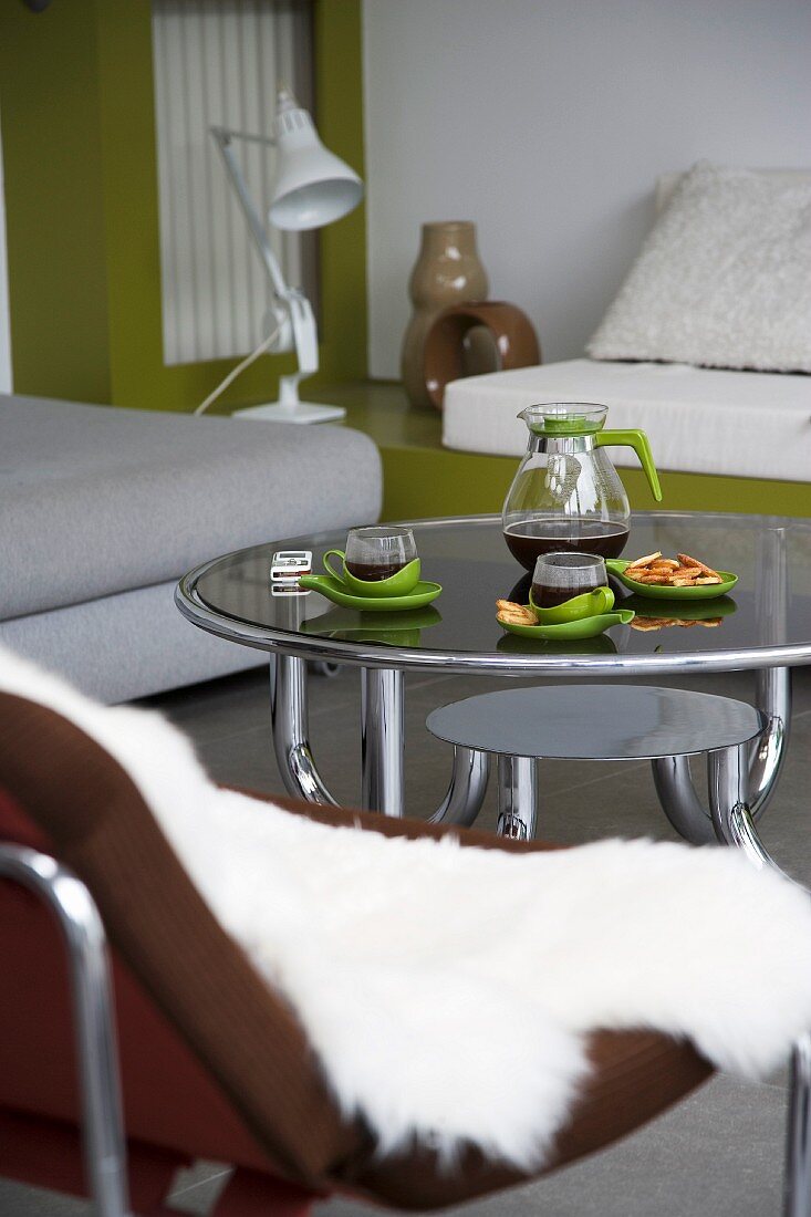 Afternoon tea - round, 70s-style coffee table with glass top and steel tube frame surrounded by various seating