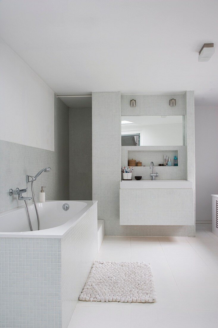 Lichtgraue Fliesen im weissen, modernen Badezimmer mit eingebautem Waschtisch vor der Duschnische