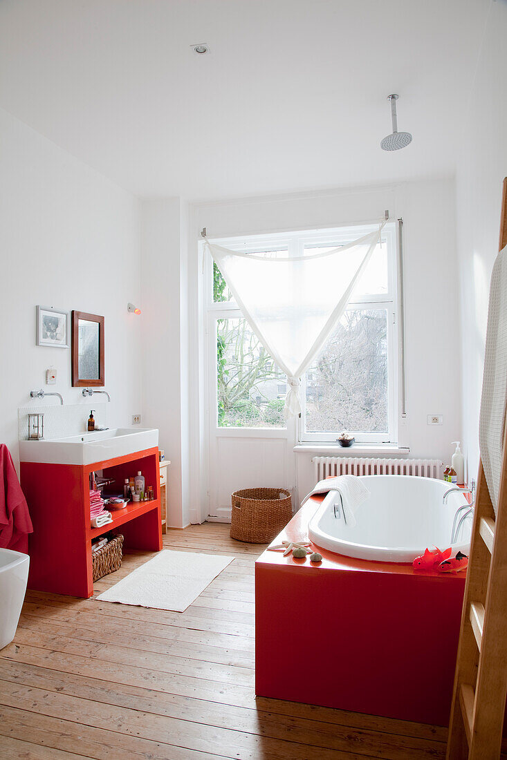 Bright bathroom with freestanding bathtub in red and white colour accents