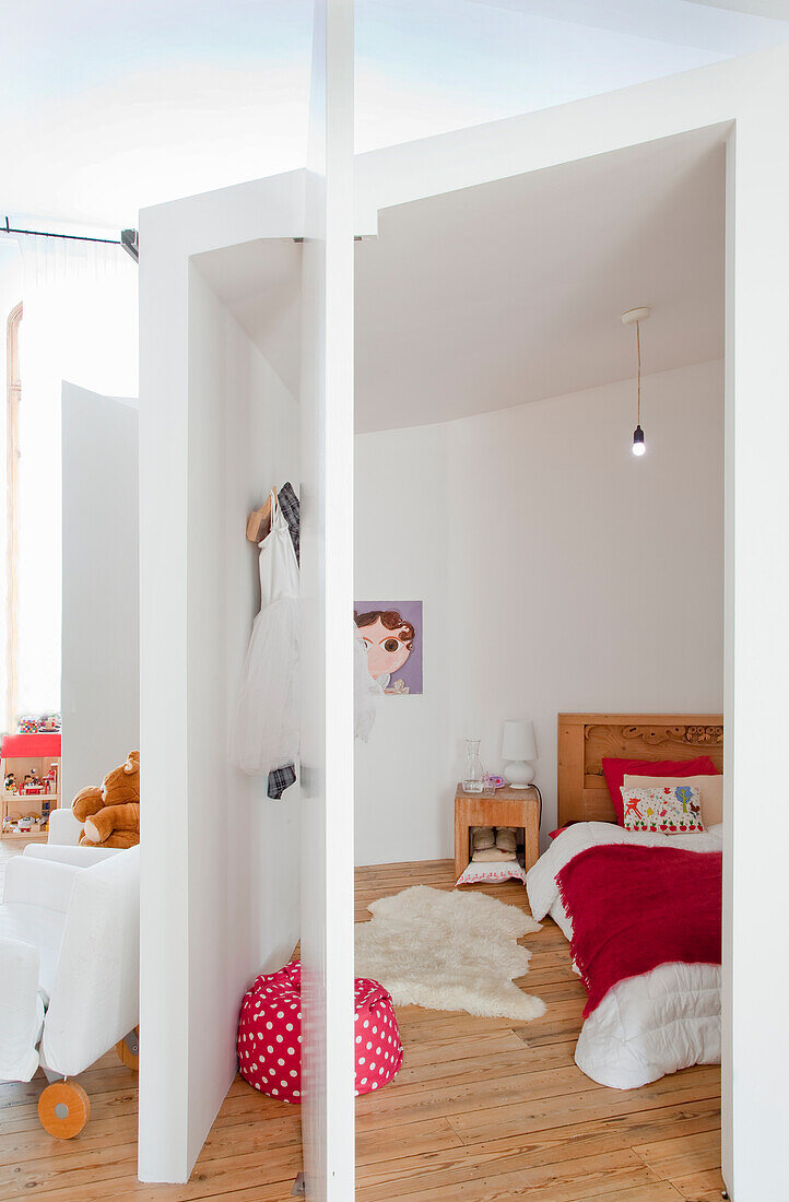 Children's room with wooden floorboards, red and white duvet cover and beanbag chair