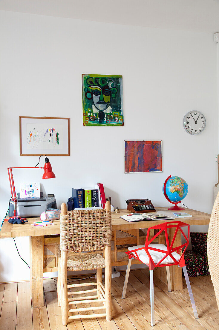 Workplace with wooden table, colourful chairs and artwork on the wall