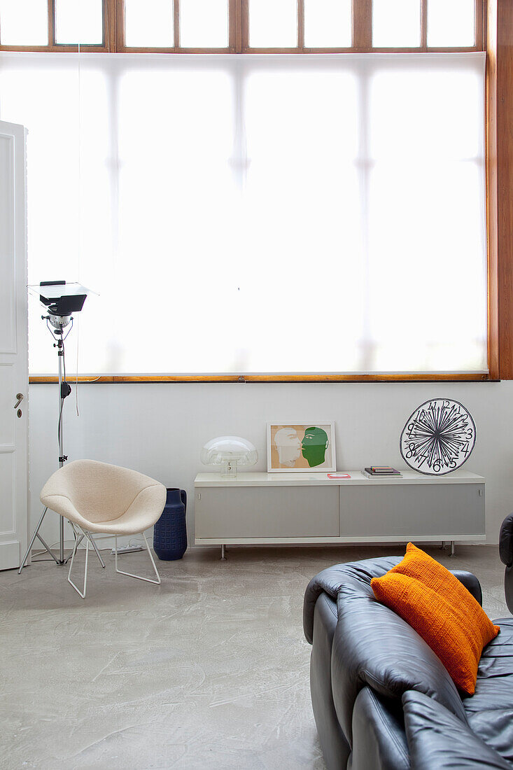 Brightly lit, modern living room with leather sofa and white sideboard