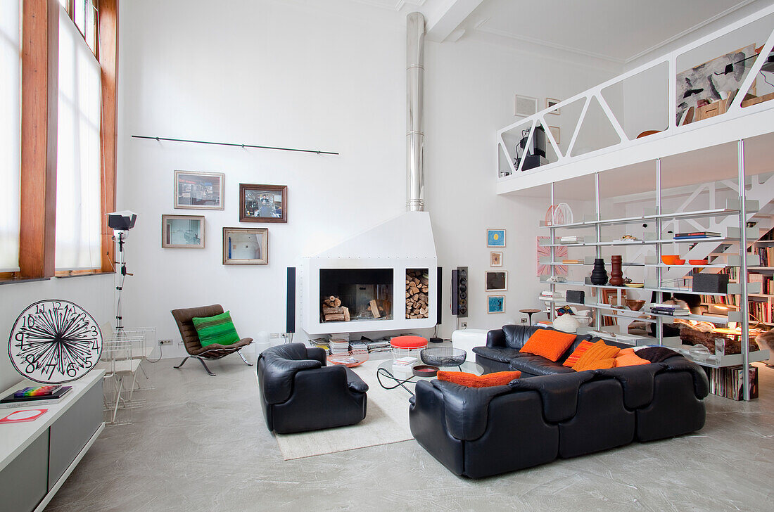 Loft living room with hanging fireplace and modern black leather sofas