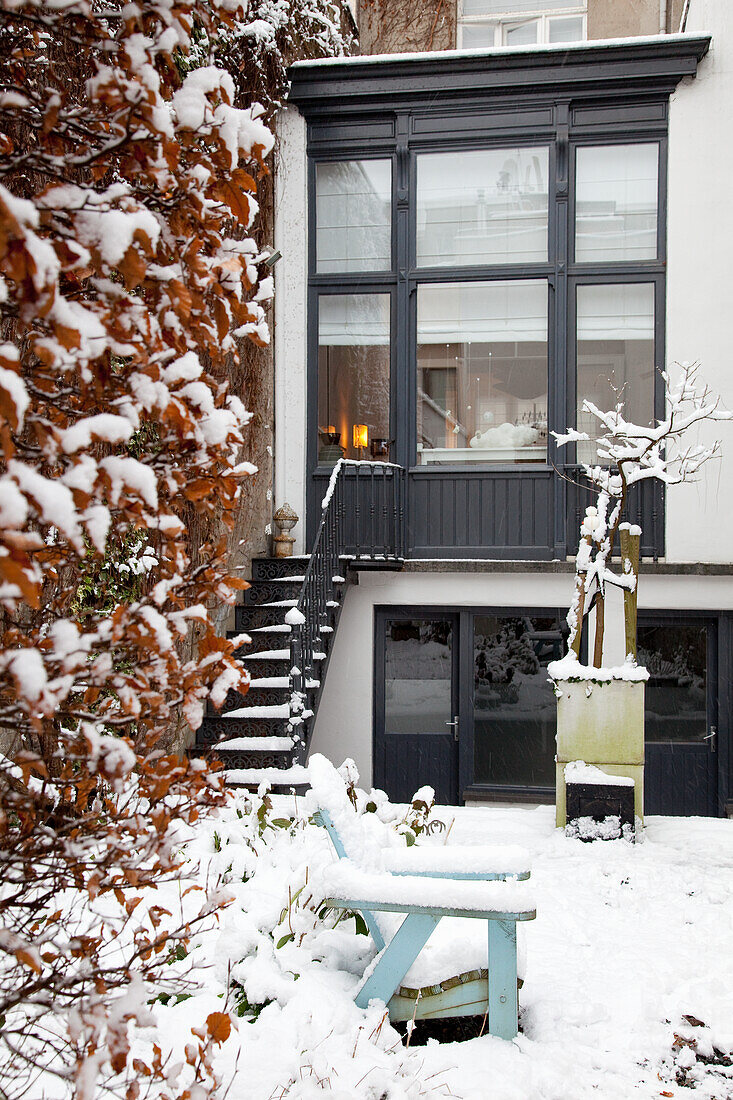 Verschneiter Terrassenzugang mit blauer Bank im Vorgarten