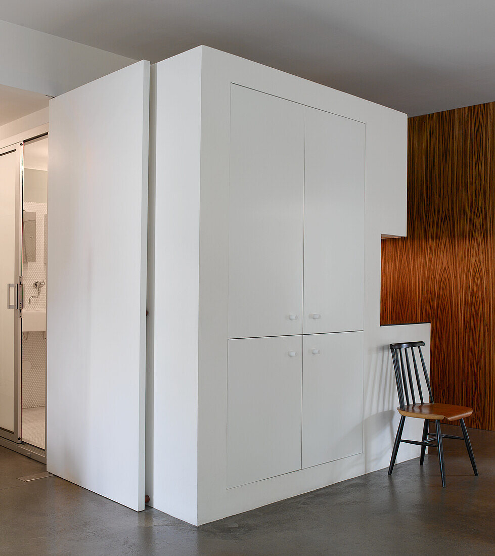 White fitted wardrobes, wall with wooden panelling and retro chair