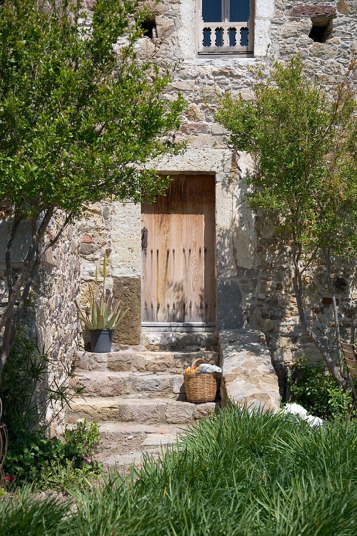 Korb auf den Eingangsstufen eines alten, mediterranen Landhauses aus Naturstein