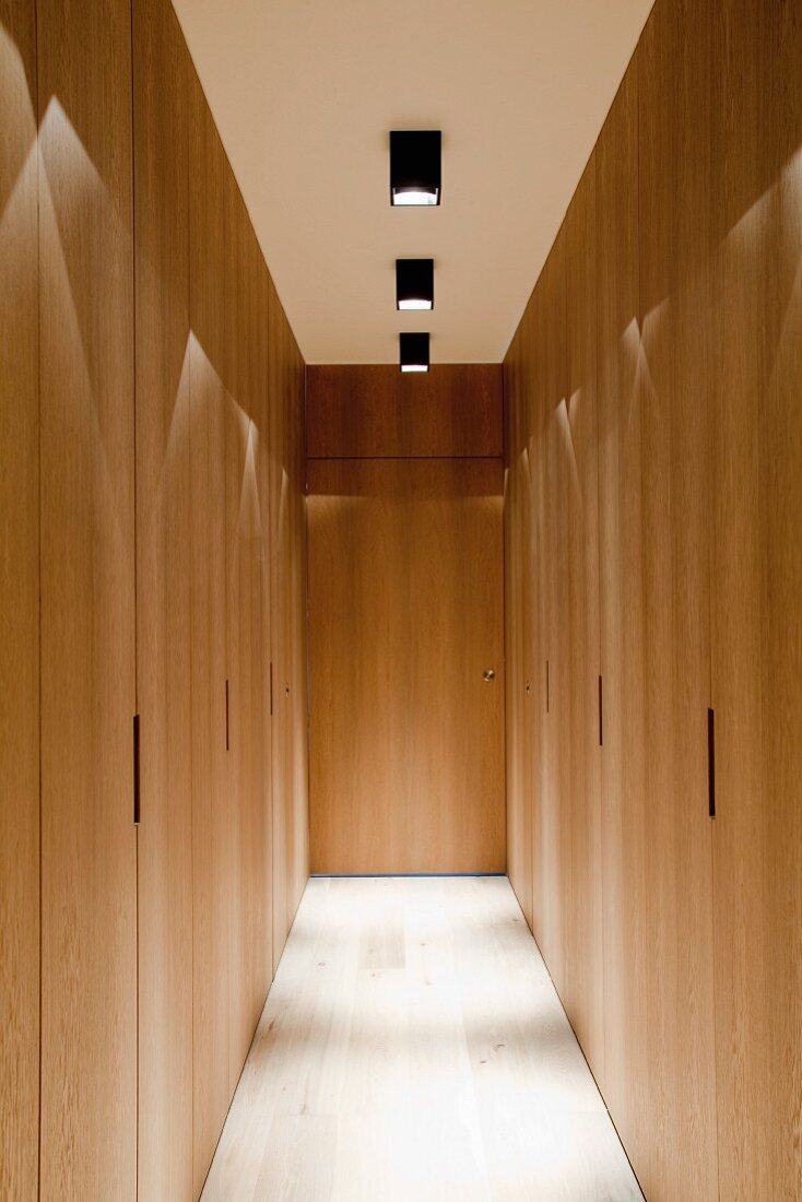 Corridor with fitted wooden cupboards and spotlights on ceiling