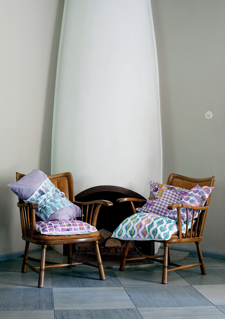 Two armchairs with patterned cushions in front of a white fireplace