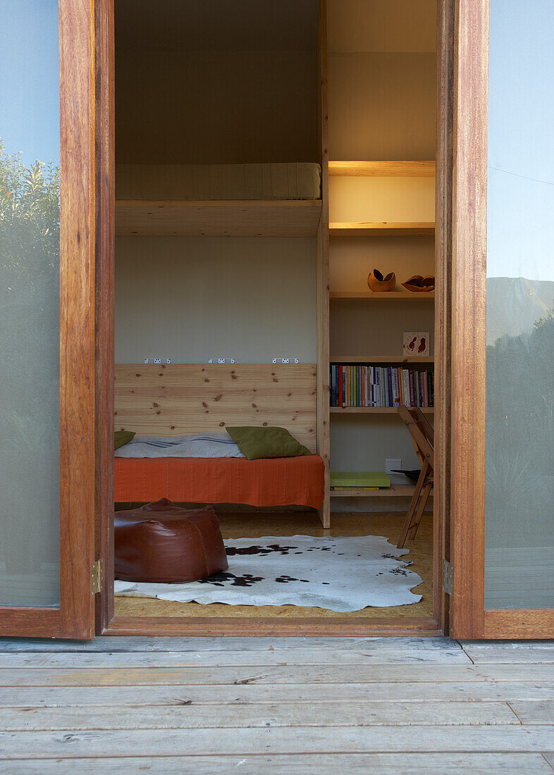 View from outside of living room with wooden bench and fur rug