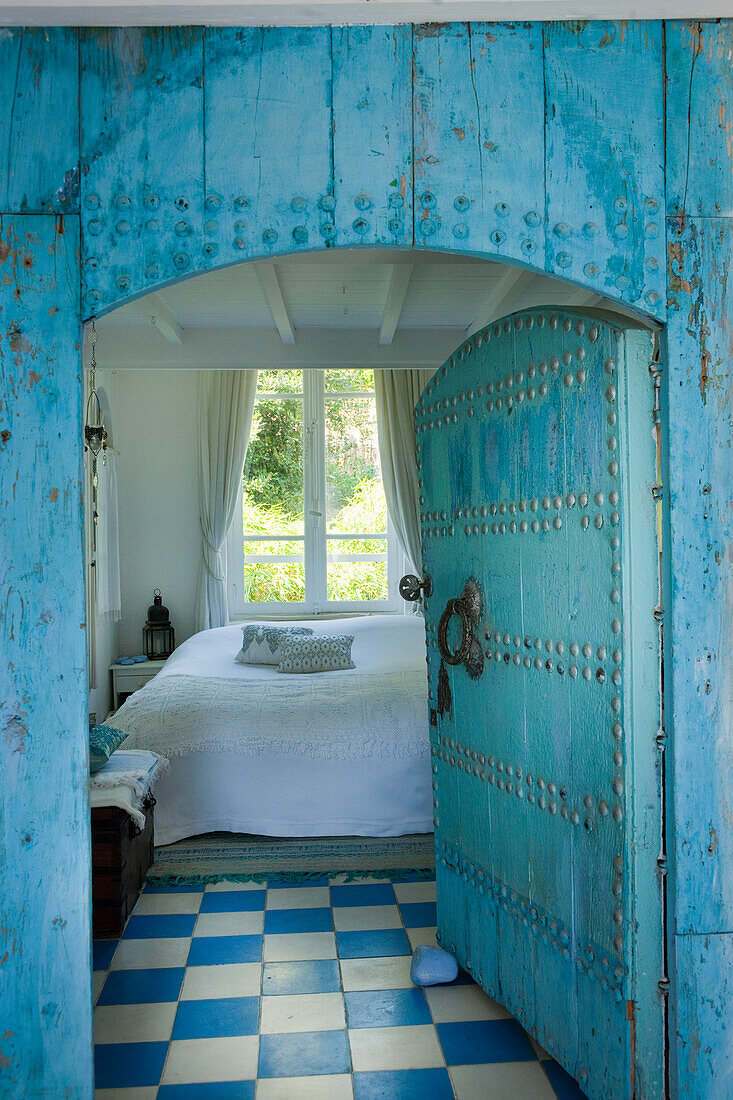 Schlafzimmer mit blau-weiß gemustertem Boden und türkisfarbener Holztür im orientalischen Stil